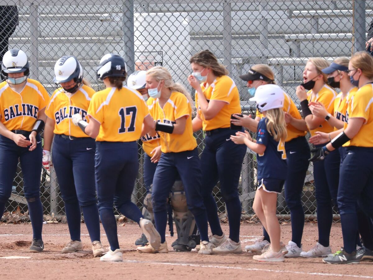 The Hornets greet junior Clara Cherry at the plate after her three-run home run during Saline's 9-run second inning.